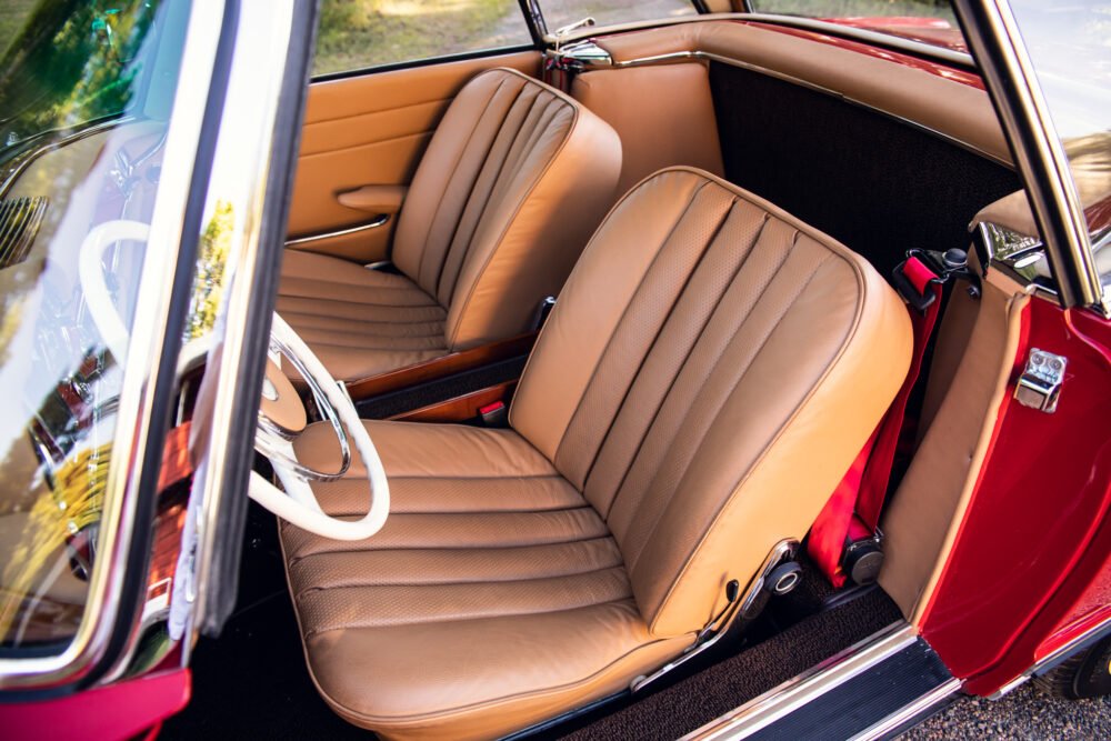 Vintage car's elegant tan interior with open door.