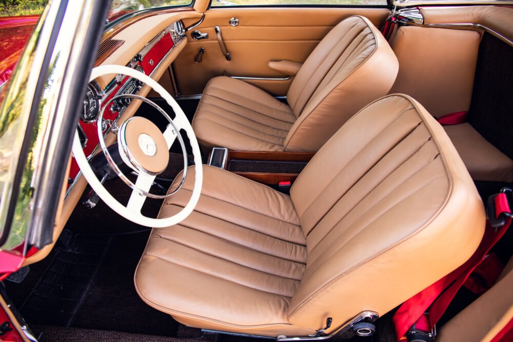 Vintage car interior with tan leather seats and wheel.