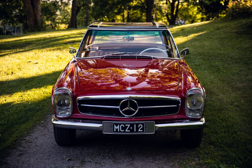 Red vintage Mercedes-Benz convertible parked outdoors.