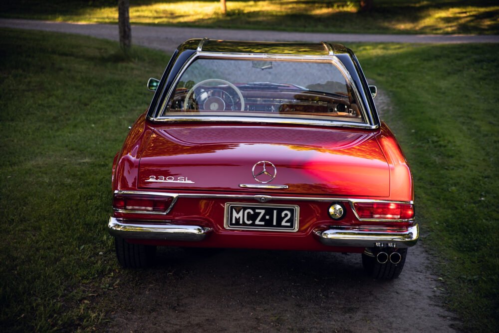 Red Mercedes 280SL convertible parked outdoors.