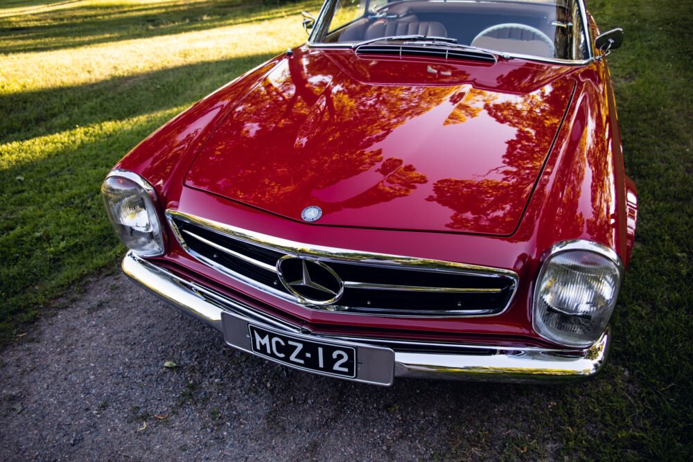 Red Mercedes-Benz classic car on grass.