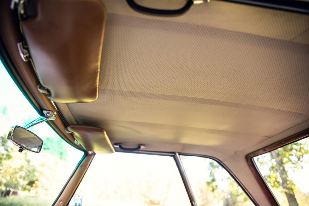 Vintage car interior, sunlit roof and rearview mirror.