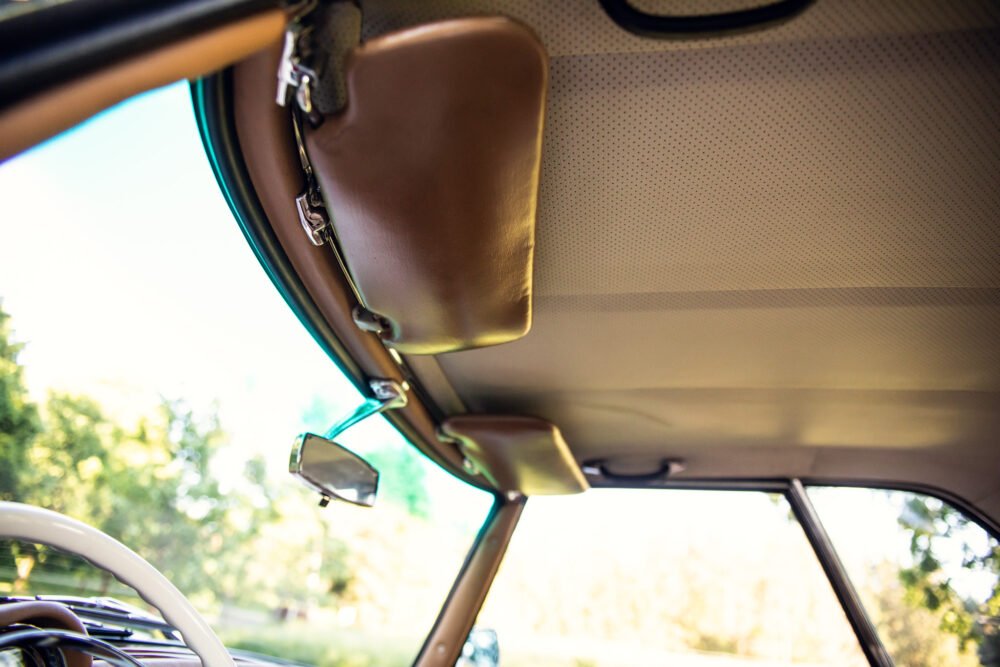 Vintage car interior with sunlit rearview mirror.