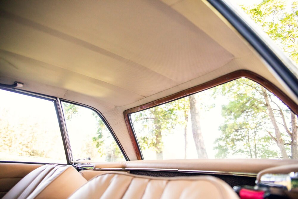 Vintage car interior with trees visible outside window.