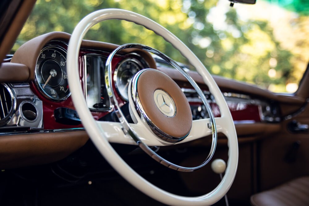 Vintage car interior with elegant white steering wheel.