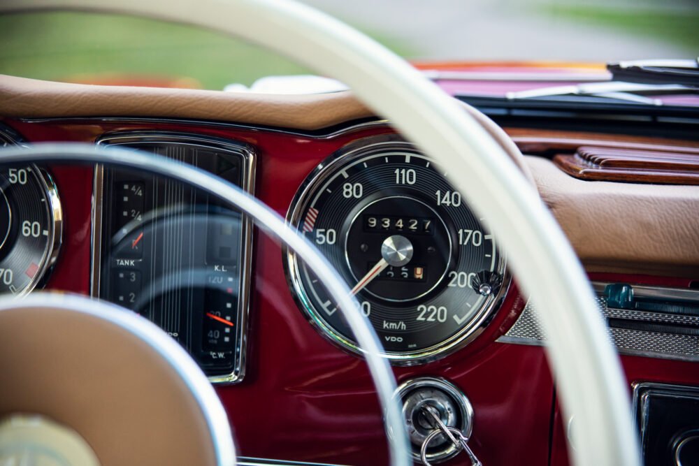 Classic car dashboard with steering wheel and gauges.