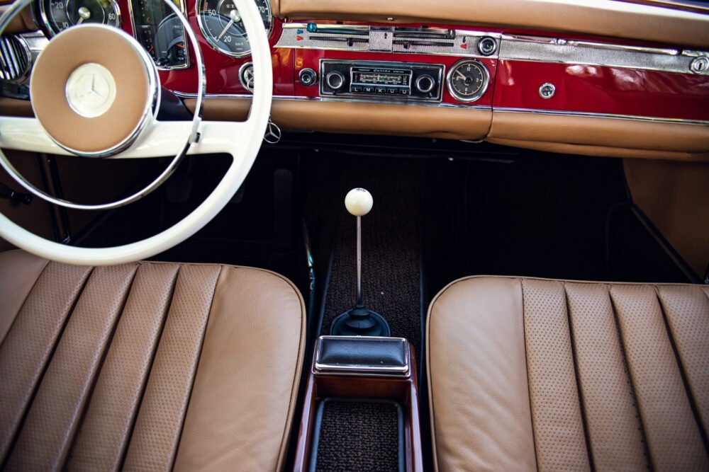 Vintage car interior with cream leather seats and dashboard.