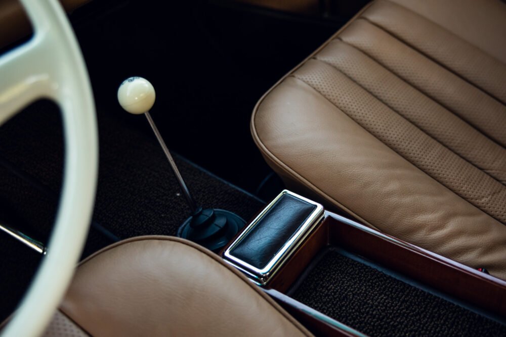 Classic car interior with leather seats and gear shift.