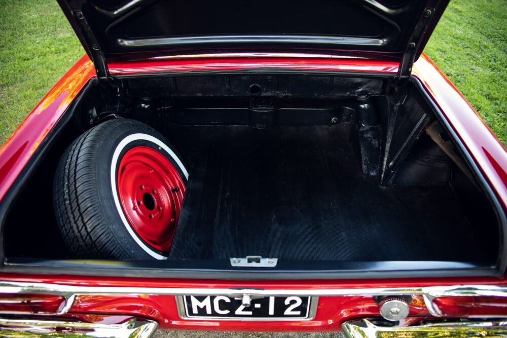 Red classic car trunk with spare tire.