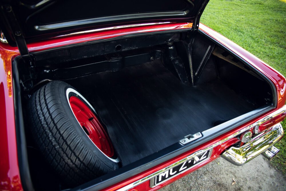 Red vintage car trunk open showing spare tire.