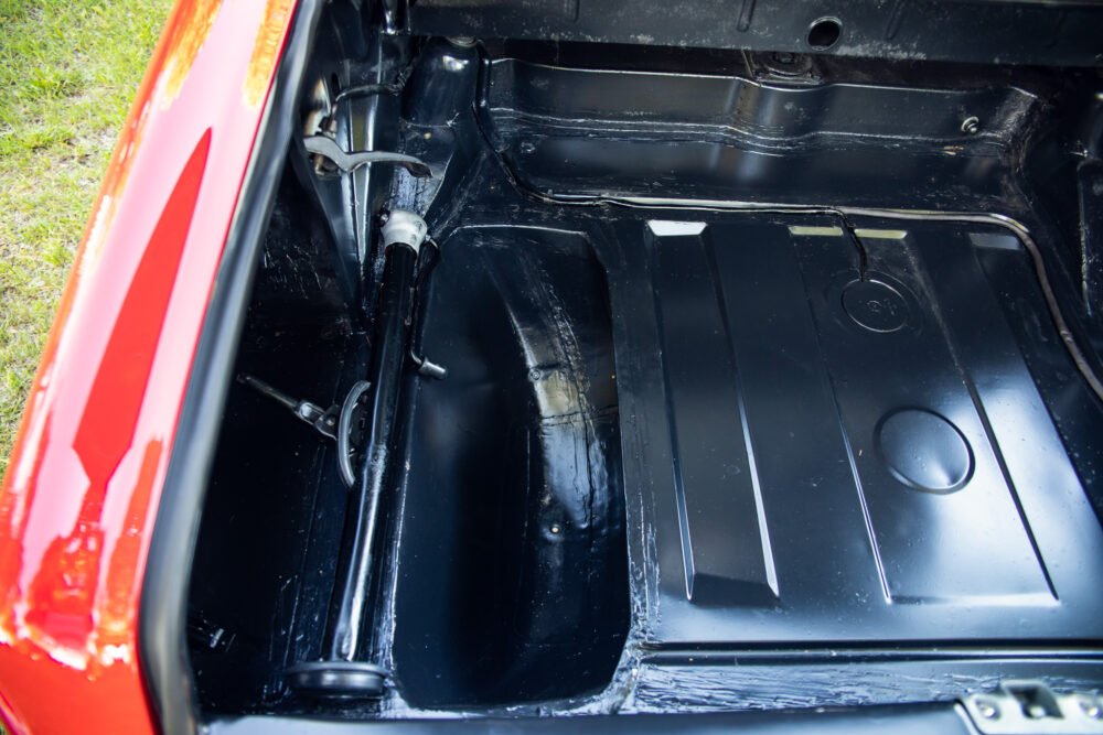 Restored car trunk interior with shiny black coating.