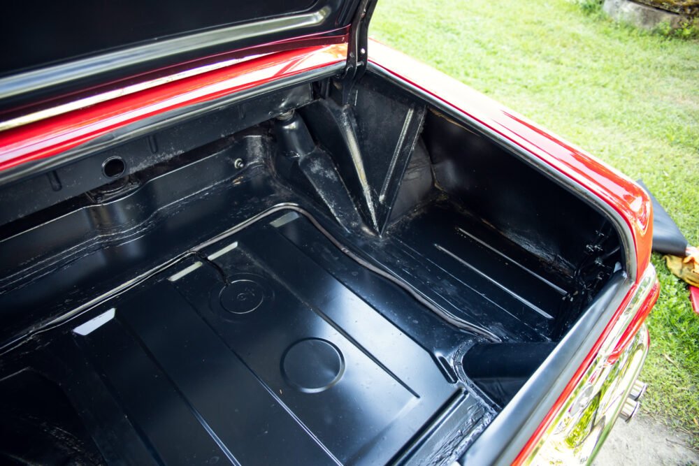 Open trunk of a red vintage car showing interior.