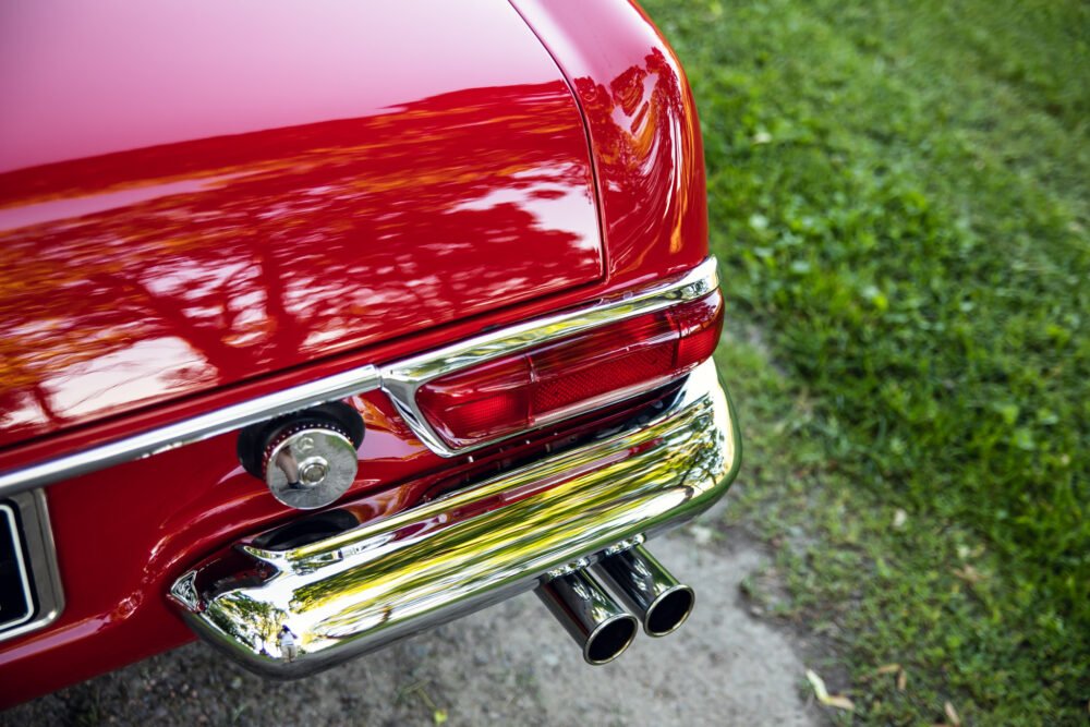 Close-up of red vintage car's rear and exhaust pipes.