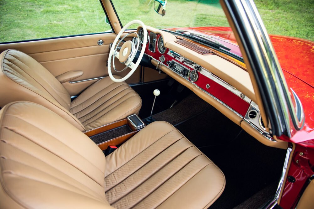 Vintage car interior with beige leather seats and dashboard.