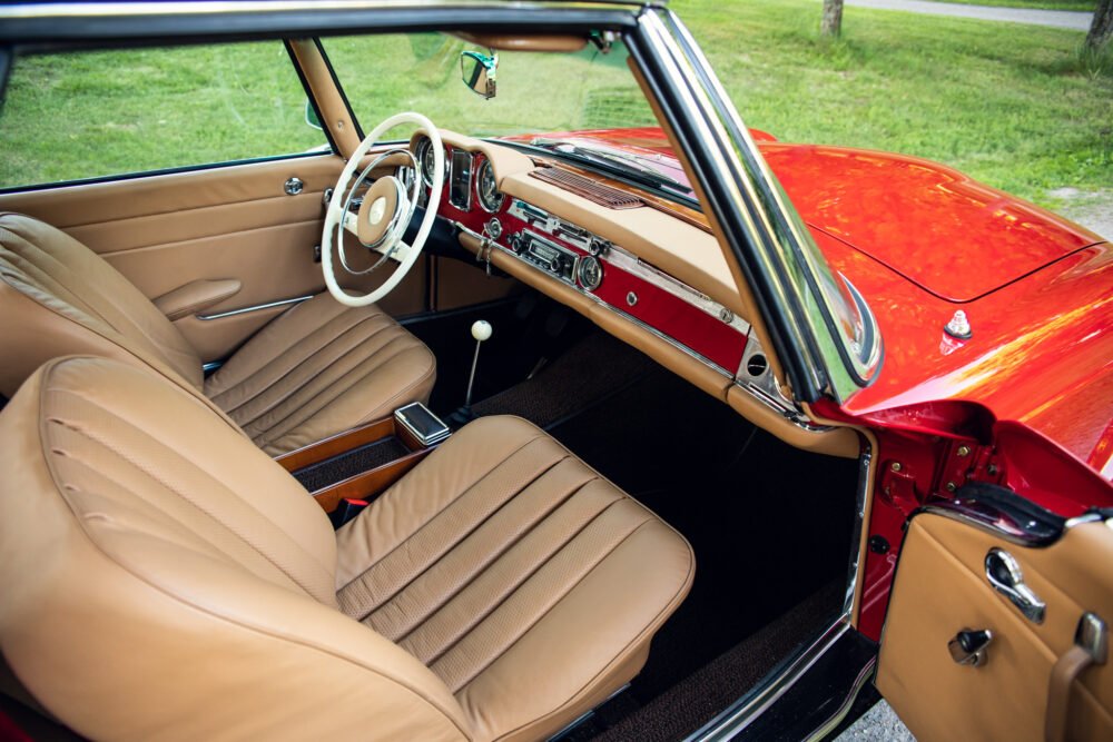 Vintage car's interior, red exterior, and tan leather seats.