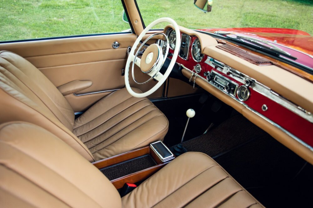 Vintage car interior, tan leather seats, classic dashboard design.