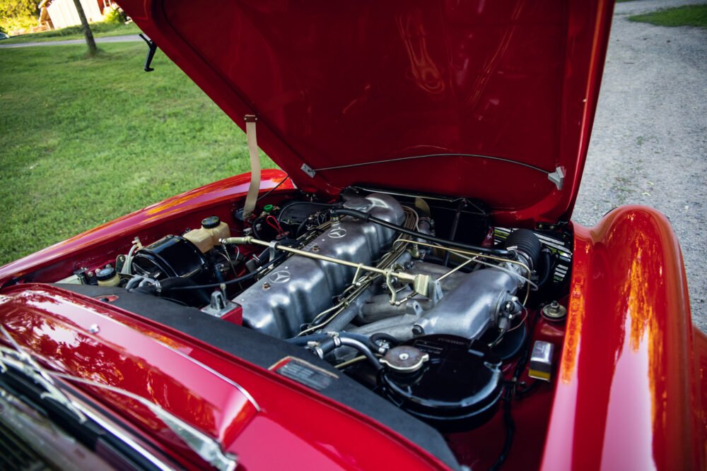 Red vintage car with open hood showing engine.