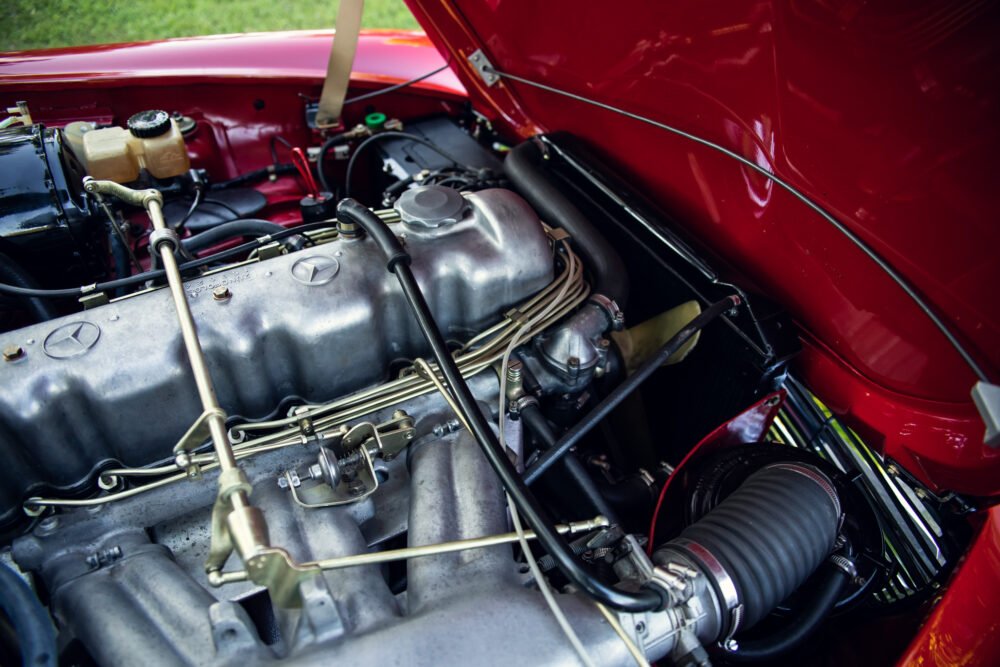 Vintage Mercedes engine in a red car, immaculately maintained.
