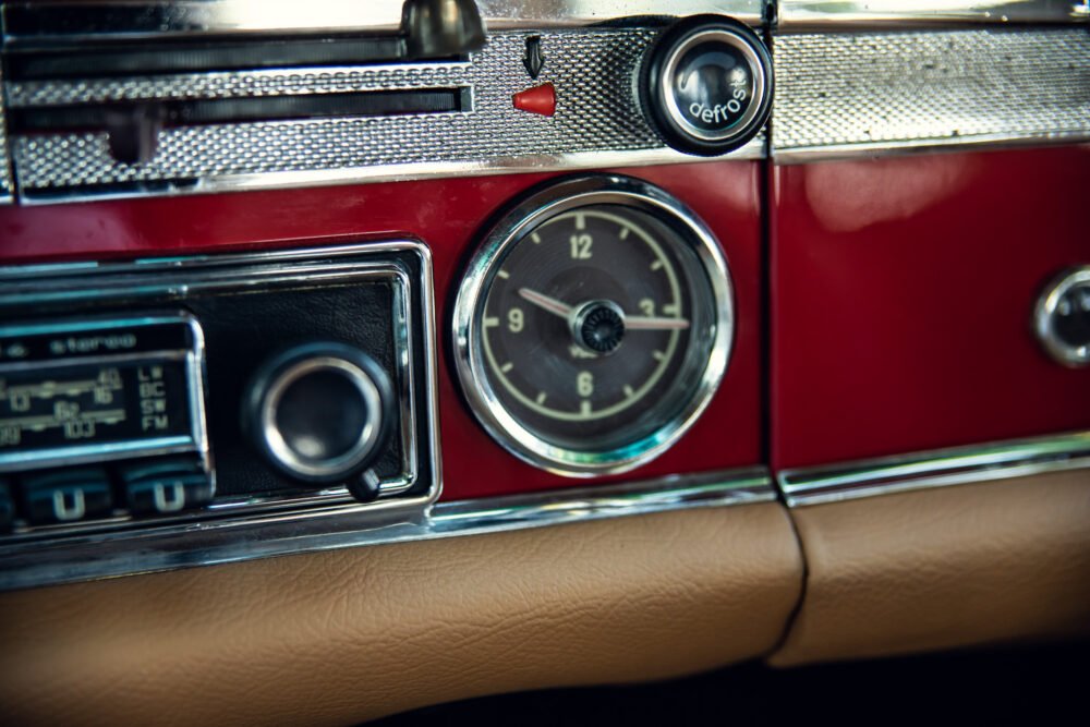 Vintage car dashboard with clock and radio.