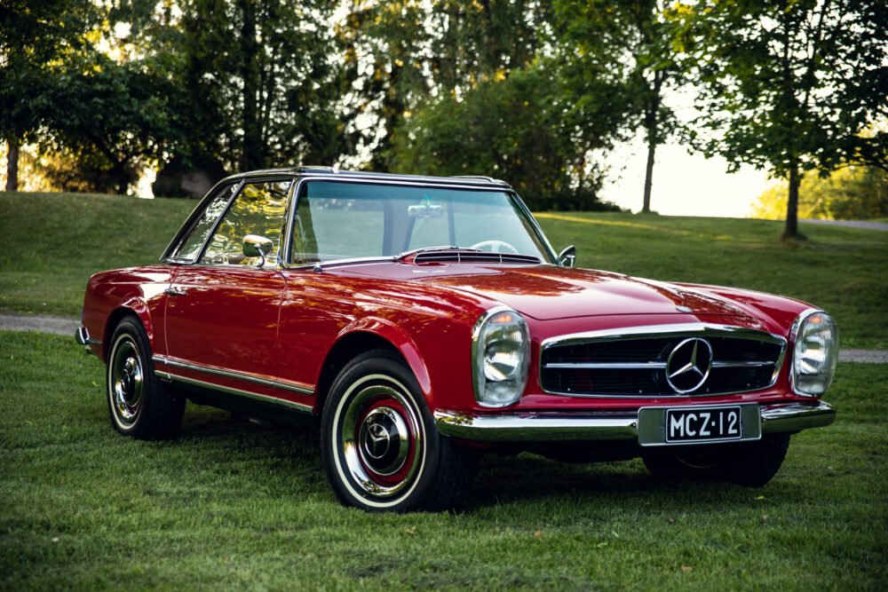 Red Mercedes-Benz convertible parked on grass.