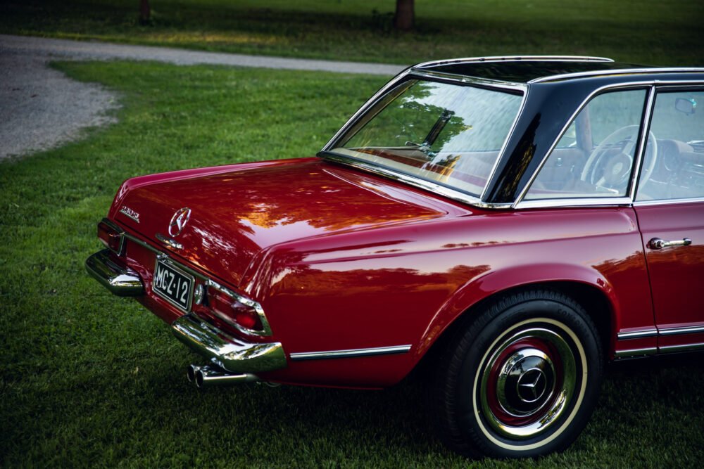 Vintage red Mercedes-Benz parked on grass.