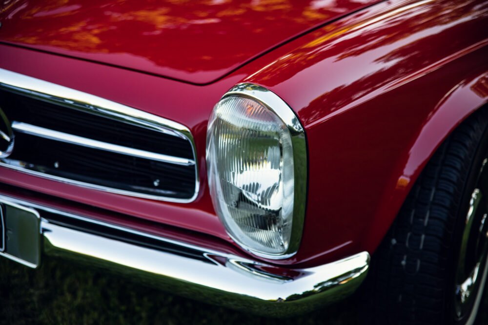 Close-up of red vintage car headlight and grille.