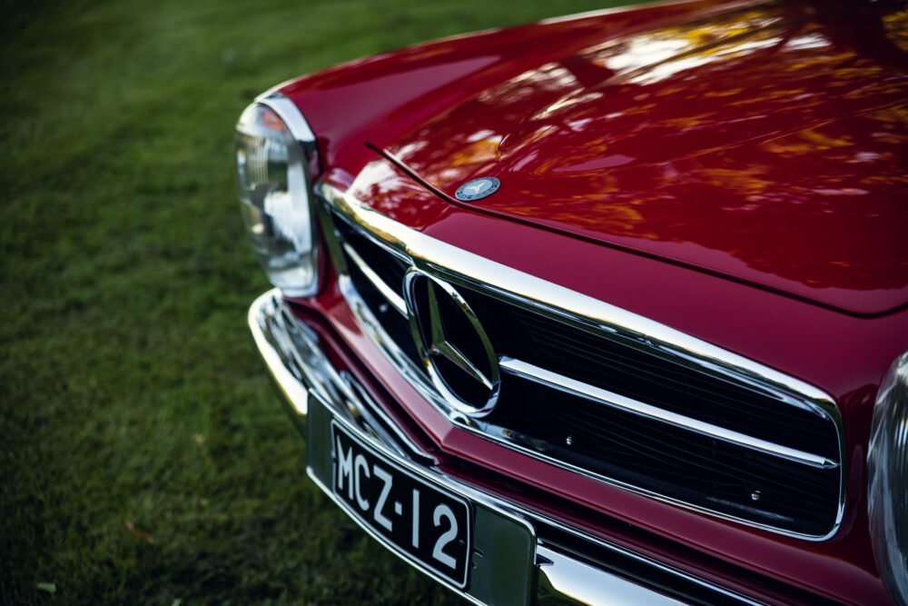 Close-up of red vintage car's front grille and headlights.