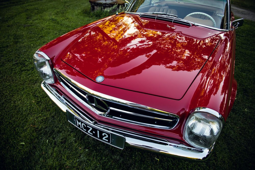 Red vintage car on green grass, close-up front view.