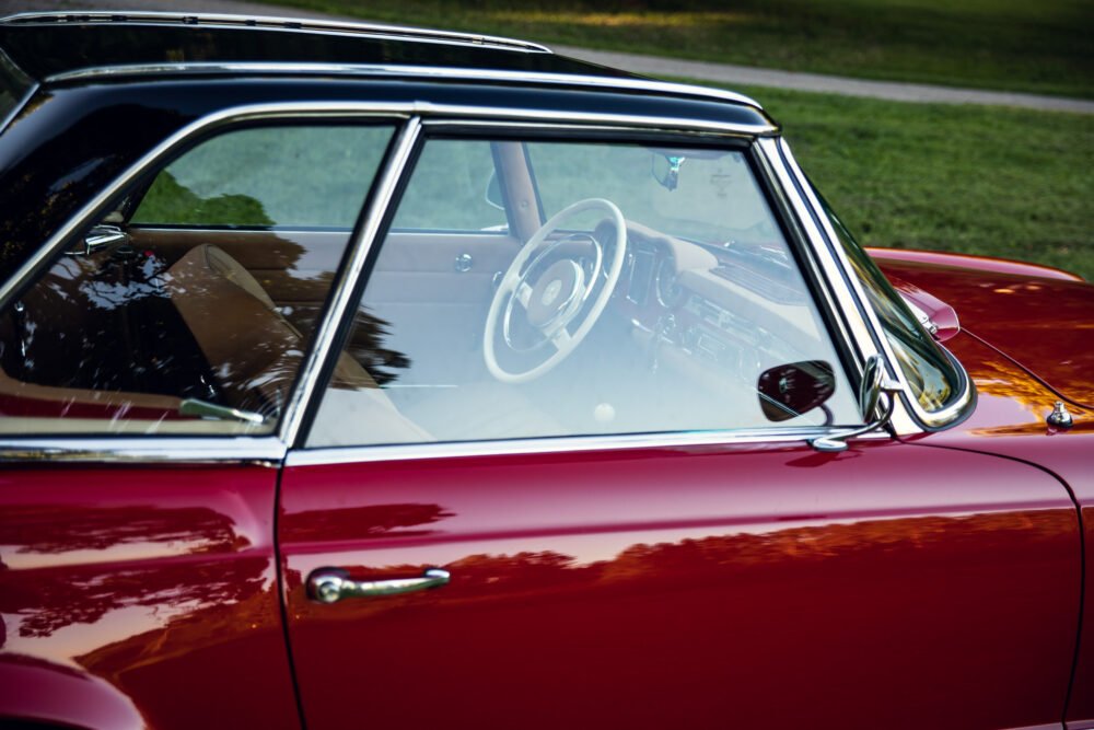 Vintage red car interior through window, classic automobile.
