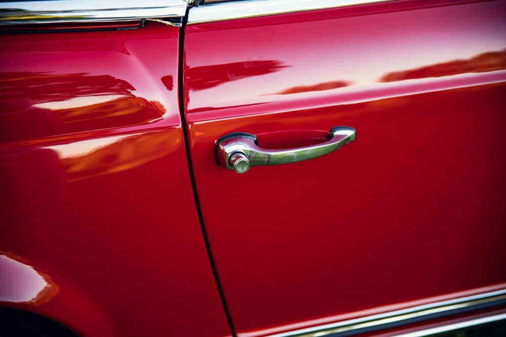 Red vintage car door and shiny chrome handle.