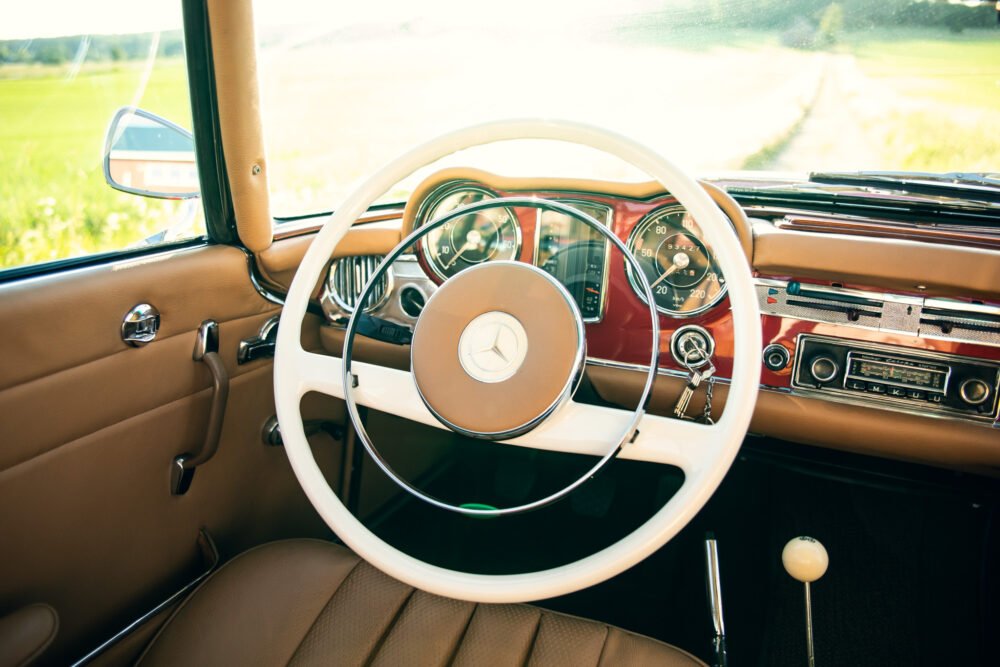 Vintage car interior with steering wheel and dashboard.