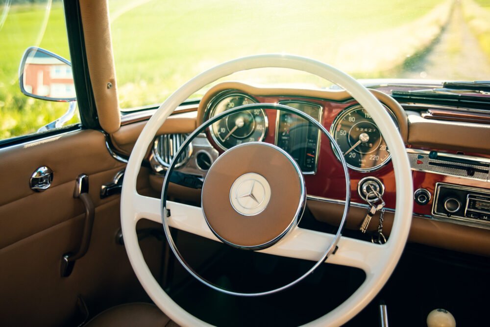 Vintage Mercedes dashboard in sunlit countryside.