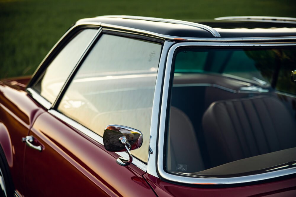 Vintage red car close-up, chrome mirror detail.