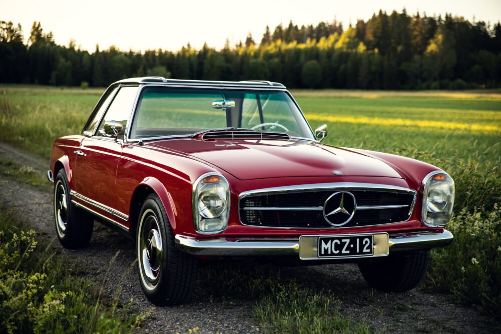 Vintage red Mercedes convertible in countryside.