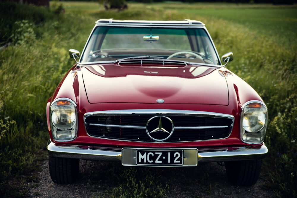 Vintage red Mercedes-Benz car in green field.