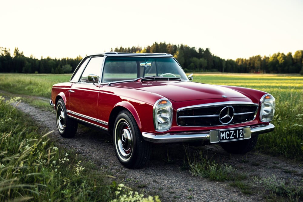 Vintage red Mercedes convertible parked in countryside.