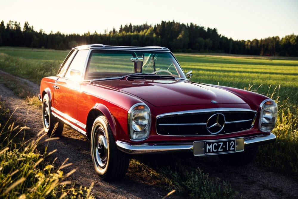 Vintage red Mercedes convertible in sunset field.