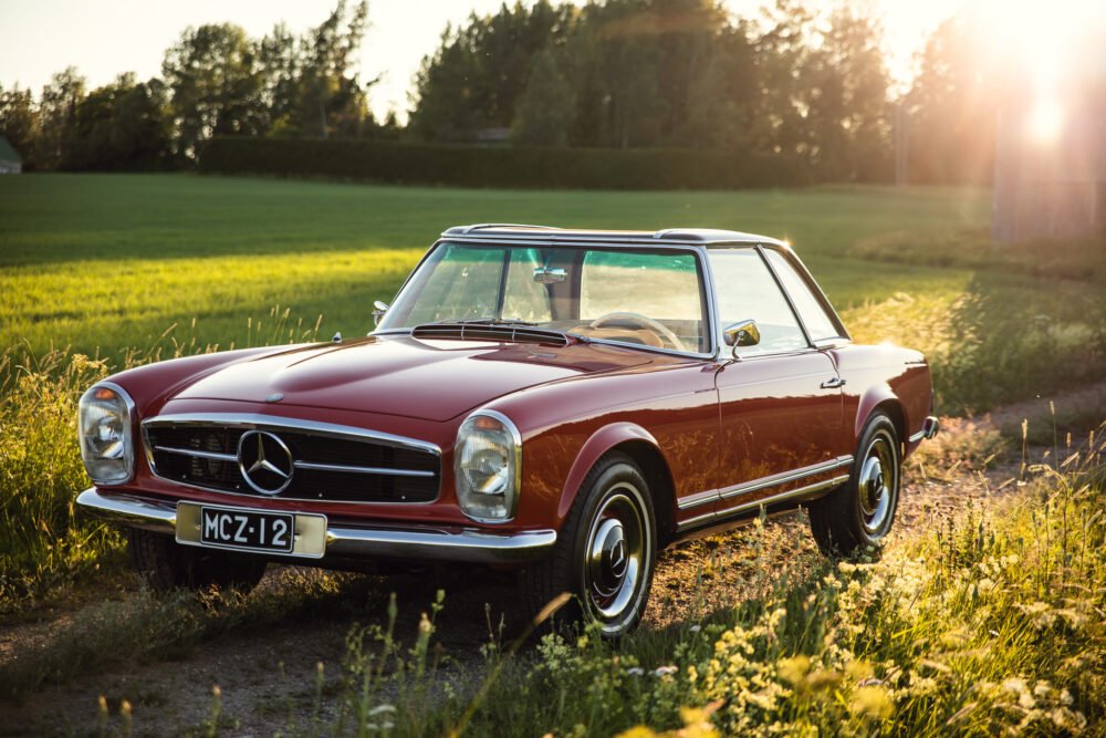 Vintage Mercedes convertible in sunset-lit countryside.