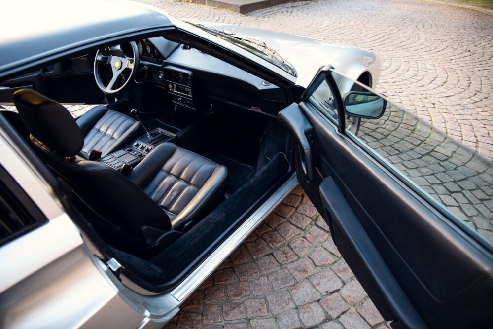 Vintage car interior with open door, luxury details.