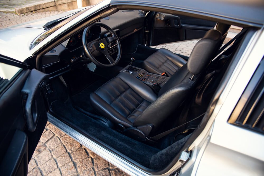 Ferrari interior showing steering wheel and leather seats.