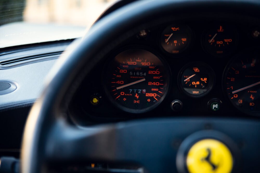 Ferrari dashboard showing illuminated gauges and logo.