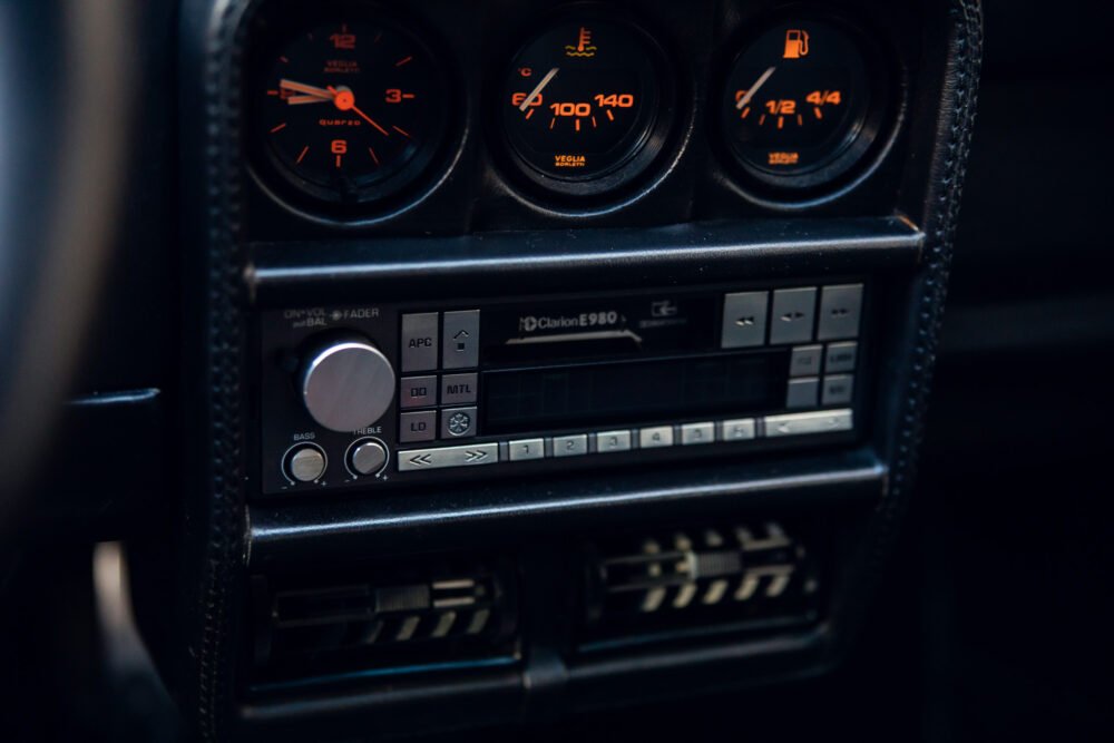 Vintage car dashboard with gauges and stereo system.