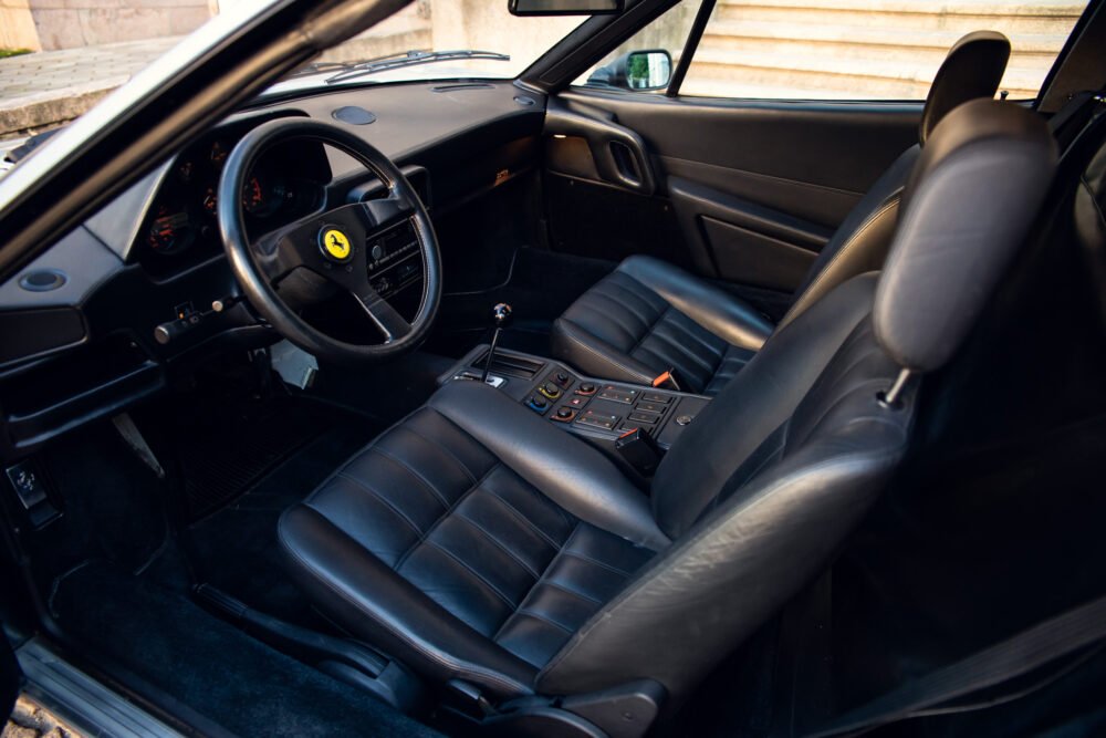 Interior of classic Ferrari with black leather seats.