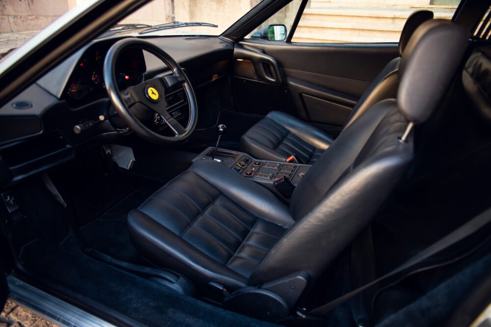Interior of vintage Ferrari with black leather seats.