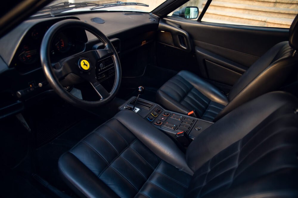 Ferrari interior with logo on steering wheel, black leather seats.