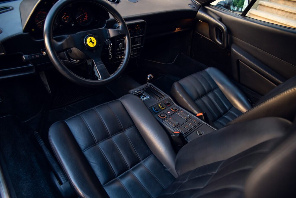 Luxury car interior with steering wheel and leather seats.