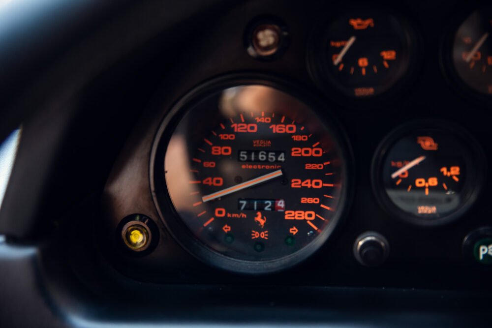 Car dashboard showing illuminated speedometer and gauges.