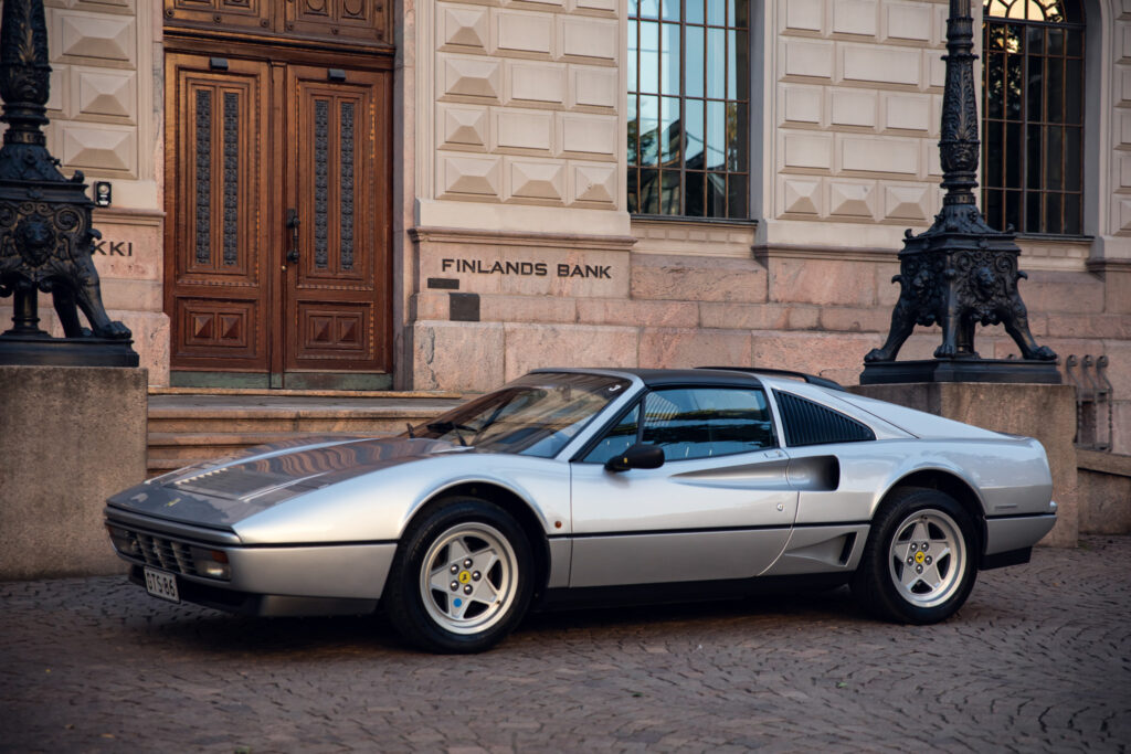 Silver sports car parked outside Finland's Bank building.