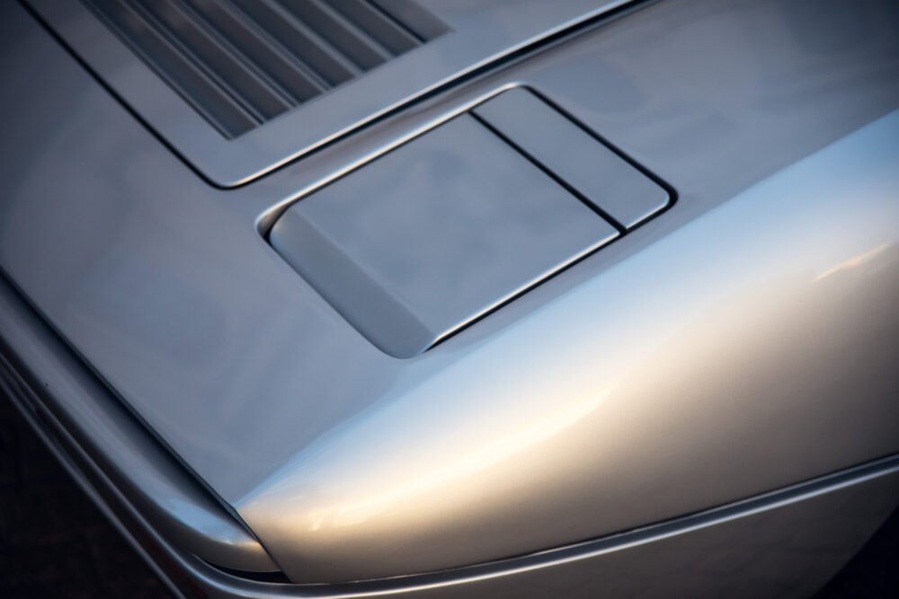 Close-up of silver car's hood and vents.