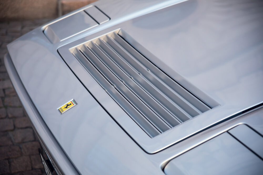 Close-up of silver Ferrari hood and emblem.